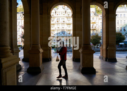 Ein Tourist zu Fuß durch die beliebte Mühlenkolonnade in der Altstadt von Karlovy Vary in der Tschechischen Republik Stockfoto