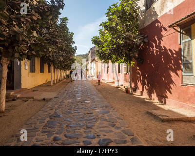 Goree, Senegal - Februar 2, 2019: Alltag und Straße mit Kopfsteinpflaster Straße zwischen Bunte Häuser auf der Insel Goree. Gorée. Dakar, Seneg Stockfoto