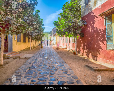 Goree, Senegal - Februar 2, 2019: Alltag und Straße mit Kopfsteinpflaster Straße zwischen Bunte Häuser auf der Insel Goree. Gorée. Dakar, Seneg Stockfoto