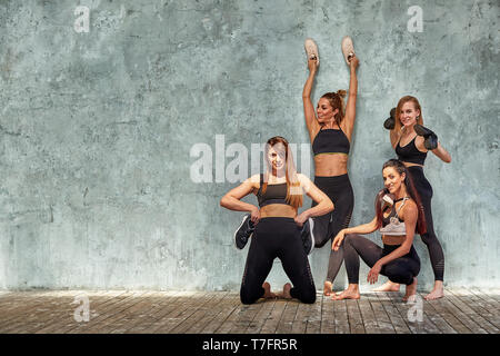 Gruppe von schönen Fitness Mädchen posieren mit Sport Zubehör gegen eine graue Wand. Platz kopieren, grauen Hintergrund. Teamwork Konzept. Stockfoto