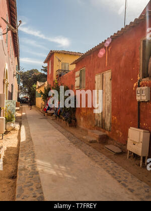 Goree, Senegal - Februar 2, 2019: Alltag und Straße mit Kopfsteinpflaster Straße zwischen Bunte Häuser auf der Insel Goree. Gorée. Dakar, Seneg Stockfoto