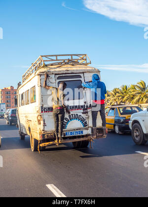 Dakar, Senegal - Februar 2, 2019: Alltag im Senegal. Alte microbus Umkreisen der Straßen, mit dem die Passagiere auf den hinteren Tür. Dakar, Senegal. Af Stockfoto