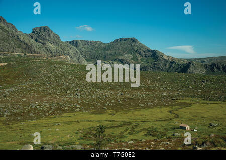 Einsamen kleinen Haus an grünen Feldern, mit Büschen und felsigen Landschaft der Serra da Estrela. Das höchste Gebirge auf dem portugiesischen Festland. Stockfoto