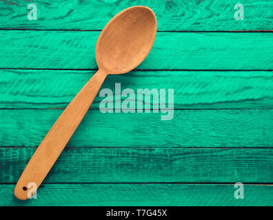 Ein Löffel aus Holz auf einem mint-farbigen Holzmöbeln rustikal Tisch. Ansicht von oben. Stockfoto