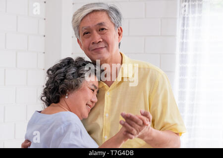 Asiatischer seniors Paar genießen Tanzen im Wohnzimmer zu Hause. Altern zu Hause Konzept Stockfoto