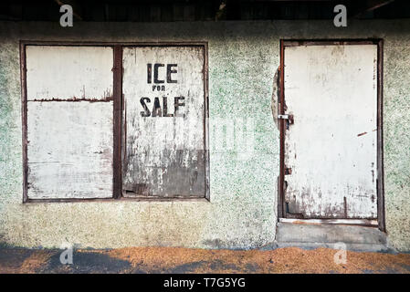 Fassade eines heruntergekommenen Shop mit geschlossenem Fenster und Türen aus Holz auf dem Markt von Leon, Provinz Iloilo, Philippinen. Eis für den Verkauf auf dem Fenster geschrieben Stockfoto