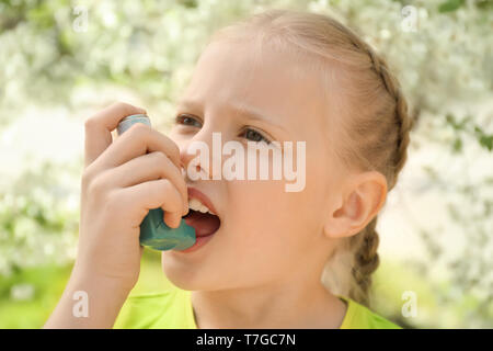 Kleines Mädchen mit Inhalator in der Nähe von blühenden Baum. Allergie-Konzept Stockfoto