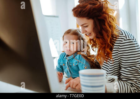 Freelancer lächelnd, während in der Nähe ihrer schönen Tochter arbeiten Stockfoto