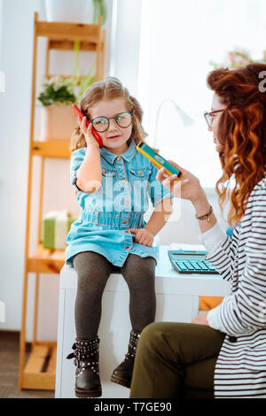 Girl holding Telefon in der Nähe des Ohrs, Vater beim Besuchen der Mama bei der Arbeit Stockfoto