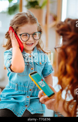 Fröhliche Tochter ruft Papa beim Besuchen der Mama bei der Arbeit Stockfoto