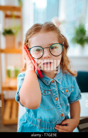 Schöne süße Mädchen tragen Denim Kleid und Gläser ihr Vati Aufruf Stockfoto