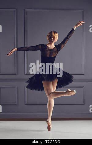 Ballerina Tänzerin in schwarzem Kleid auf grauen Hintergrund posiert. Stockfoto