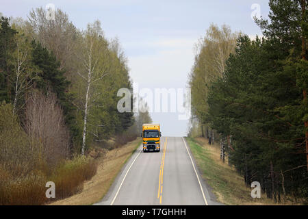 Salo, Finnland - 26 April 2019: Straße Landschaft an einem Tag des Frühlings mit gelben und grünen Renault Trucks T Auflieger für den Transport von Ladung. Stockfoto