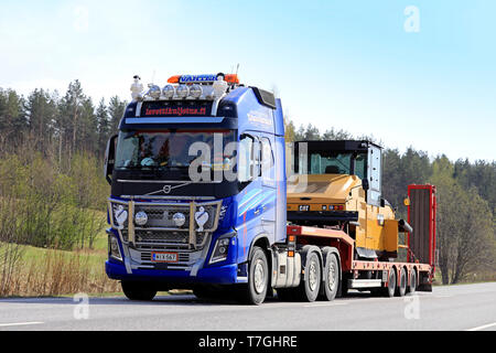 Salo, Finnland - 26 April 2019: Volvo FH 16 750 Auflieger von Lavettikuljetus Ylitalo & Vahtera Oy hols Cat CW 34 Gummiradwalze entlang der Autobahn. Stockfoto