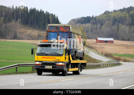 Salo, Finnland - 26 April 2019: Gelb Mitsubishi Fuso Canter Abschleppwagen trägt eine alte Gliederung van entlang der Autobahn an einem Tag des Frühlings. Stockfoto