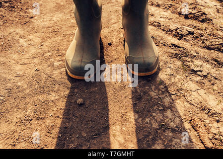 Bauer stehen auf Schmutz Country Road, in der Nähe von Gummi Gummistiefel Stockfoto