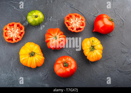 Auswahl an Bio große heirloom Tomaten auf dunkelblau konkreten Hintergrund, Ansicht von oben, selektiver Fokus Stockfoto