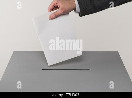 Grau zur Wahlurne. Die Präsidentschafts- und Parlamentswahlen. Der Wähler wirft die Stimmzettel in die Wahlurne. Stockfoto