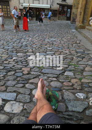 Pilgrom ruht in der historischen Altstadt von Conques während des Tages, die sich entlang der Via Podiensis n Süd Frankreich. Neben Abbey-Church der Saint-Foy. Stockfoto