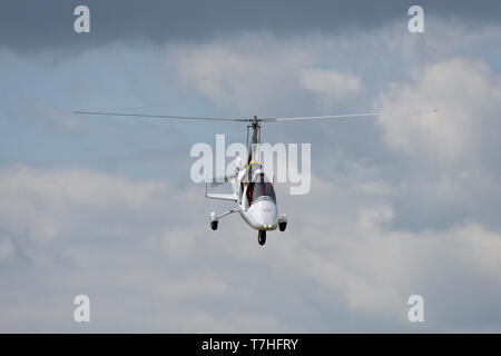 Eine Rotorsport gyrocopter G-CIRT steigt für eine Landung am Popham Flugplatz in Hampshire am Frühling Fly-in Event. Stockfoto
