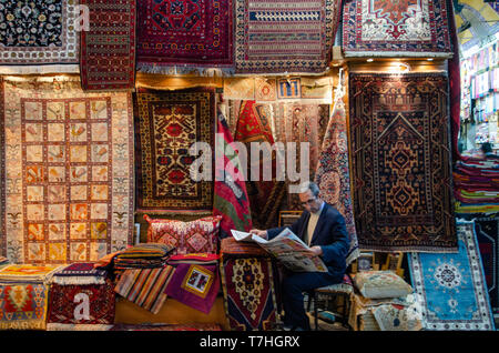 Ein Türkischer Teppich Verkäufer eine Zeitung lesen innerhalb der Grand Bazar, Istanbul, Türkei Stockfoto