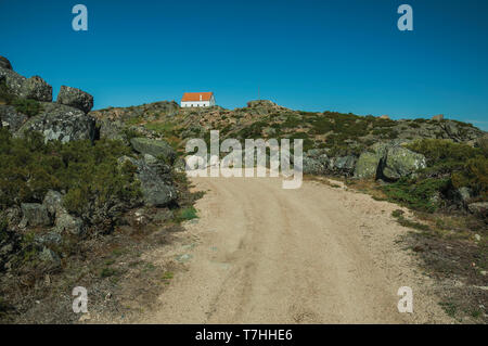 Trail durch Felsen in den Highlands mit einem einsamen Haus an der Oberseite, in der Serra da Estrela. Das höchste Gebirge auf dem portugiesischen Festland. Stockfoto