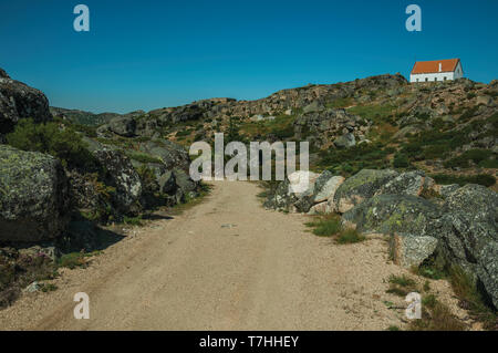 Trail durch Felsen in den Highlands mit einem einsamen Haus an der Oberseite, in der Serra da Estrela. Das höchste Gebirge auf dem portugiesischen Festland. Stockfoto