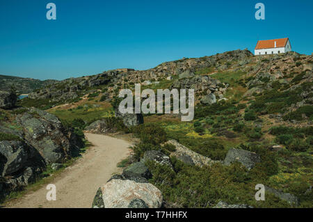 Trail durch Felsen in den Highlands mit einem einsamen Haus an der Oberseite, in der Serra da Estrela. Das höchste Gebirge auf dem portugiesischen Festland. Stockfoto