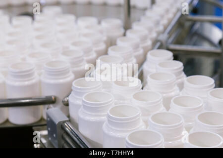 Weißer Kunststoff Flasche auf der Produktionslinie des Förderbandes an der Füllmaschine im medizinischen Werk. Selektive konzentrieren. Stockfoto