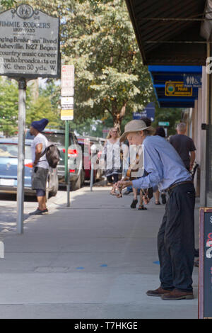 ASHEVILLE, North Carolina, USA - 9. September 2018: Eine ältere Geiger Solo spielt für Tipps auf einer belebten Zentrum von Asheville Straße neben einem Schild comm Stockfoto