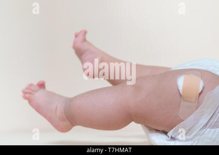 Baby Junge Beine mit einem band-aid Patch nach der Einnahme ein Impfstoff. Arzt oder Krankenschwester, Pflaster auf Baby Bein im Krankenhaus. Stockfoto
