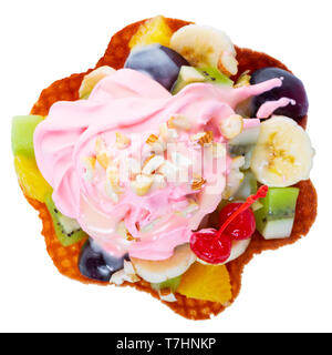 Blick von oben auf die gewürfelten Früchten im Waffle rosa Kegel Schüssel mit Sahne und Nüssen dekoriert maraschino Kirsche ist auf weißem Hintergrund Stockfoto