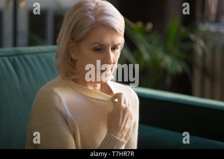 Grauhaariger reife Frau in Pullover leiden unter hoher Temperatur Stockfoto