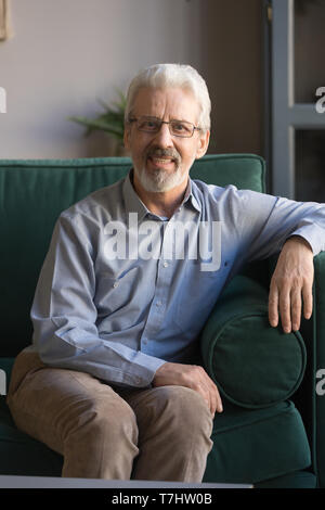 Vertikale Portrait von grauen Haaren reifer Mann saß auf der Couch Stockfoto
