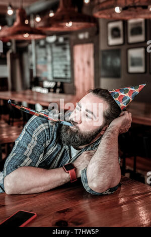 Frustriert pub Gast seine Partei Horn blasen. Stockfoto