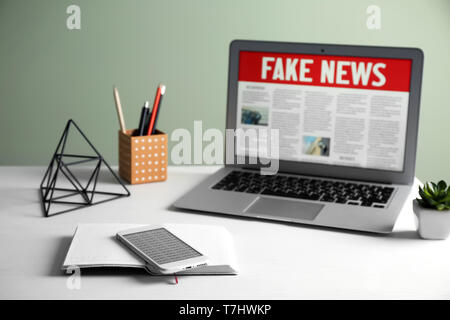 Notebook, Handy und Laptop mit Worten gefälschte Nachrichten auf dem Bildschirm im Zimmer Stockfoto