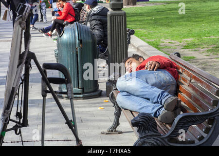 Lemberg, Ukraine - 14. April 2019: Obdachlosen schlafen mit Zigarette auf der Holzbank auf der Stadt. Stockfoto