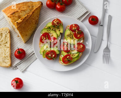 Zwei Sandwiches und Tapas mit verschiedenen Gemüsen, wie Avocado, Tomate und frischem Thymian funkelten mit Pinienkernen vorbereitet. Gesundes Essen im White w Stockfoto