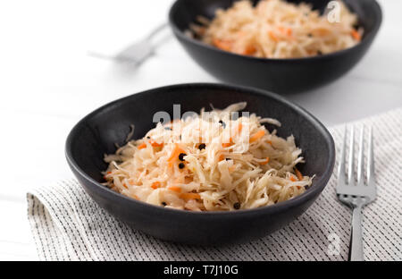 Fermentierter Kohl. Zwei Platten der traditionellen russischen Vorspeise Sauerkraut mit Karotte auf weissem Holztisch. Stockfoto