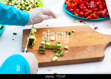 Nahaufnahme von Hand schneiden Zucchini eines Kindes auf einem Holzbrett Stockfoto