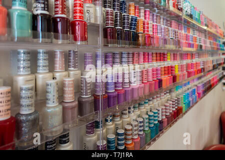 Flaschen von bunten Nagellack auf ordentlich auf Anzeige auf Regalen in einem Nagelstudio angeordnet. Stockfoto