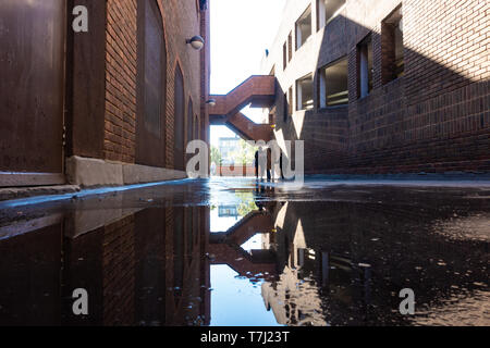 70er Jahre Architektur spiegelt sich in einer Pfütze nach einer Dusche. Stockfoto