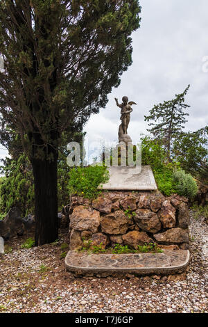 Das Grab mit der Skulptur der Engel in der Nähe der Zypressen auf dem Montjuic Friedhof in bewölkten Tag, Barcelona, Katalonien, Spanien Stockfoto