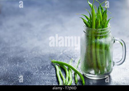 Grüne Bohnen im Glas auf grauem Stein. Kopieren Sie Platz. Stockfoto