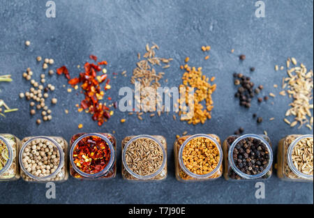 Sortimente von Gewürzen in Töpfen auf grauem Stein. Ansicht von oben. Kopieren Sie Platz. Stockfoto