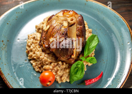 Zerfetztes Fleisch Gericht mit garniert mit Gemüse auf einem blauen Platte eingerichtet. Dunklen Hintergrund. Stockfoto