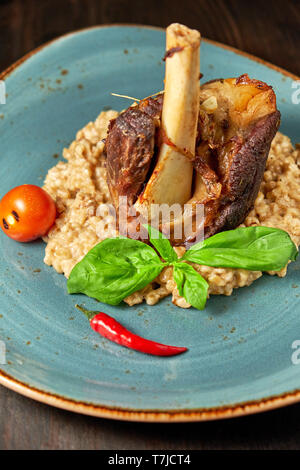 Zerfetztes Fleisch Gericht mit garniert mit Gemüse auf einem blauen Platte eingerichtet. Dunklen Hintergrund. Stockfoto