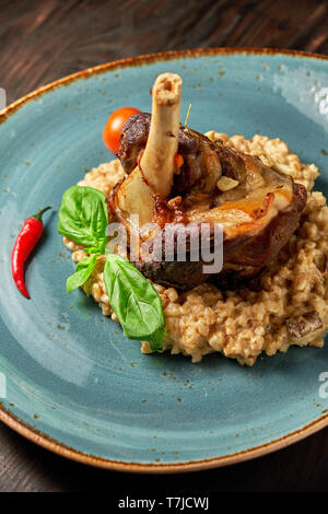 Zerfetztes Fleisch Gericht mit garniert mit Gemüse auf einem blauen Platte eingerichtet. Dunklen Hintergrund. Stockfoto