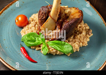 Zerfetztes Fleisch Gericht mit garniert mit Gemüse auf einem blauen Platte eingerichtet. Dunklen Hintergrund. Stockfoto