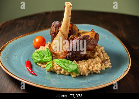 Zerfetztes Fleisch Gericht mit garniert mit Gemüse auf einem blauen Platte eingerichtet. Dunklen Hintergrund. Stockfoto